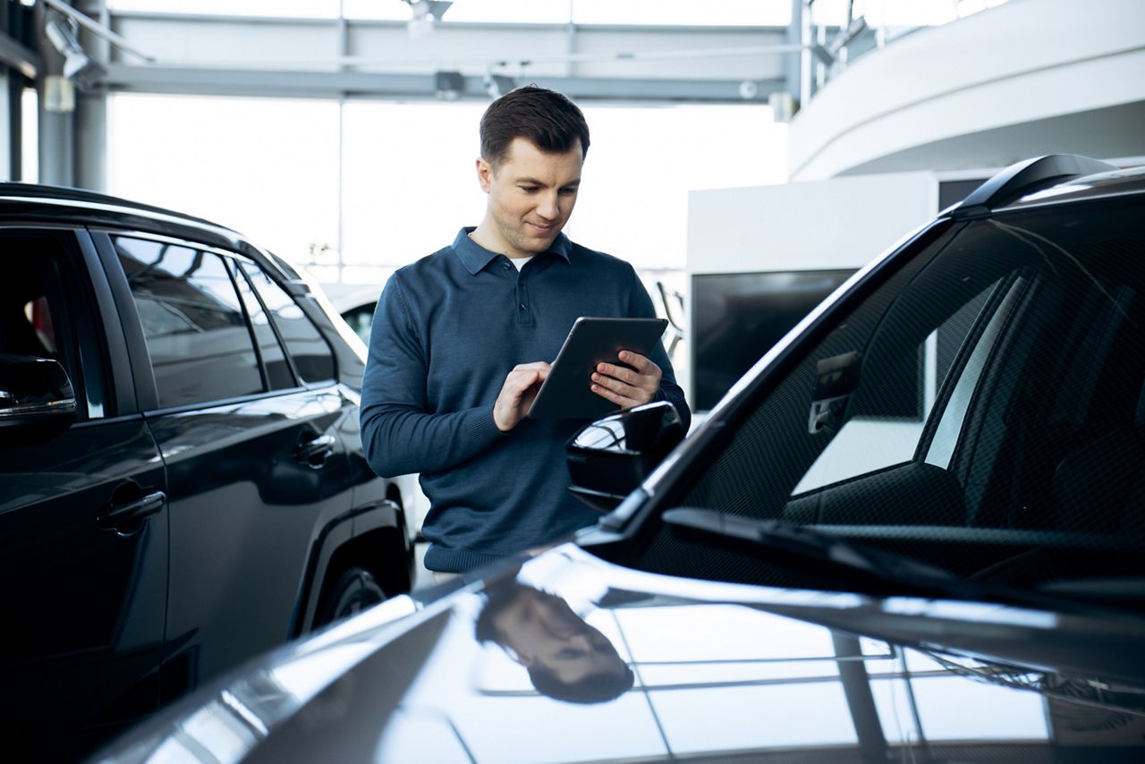 man using a tablet in automotive showroom