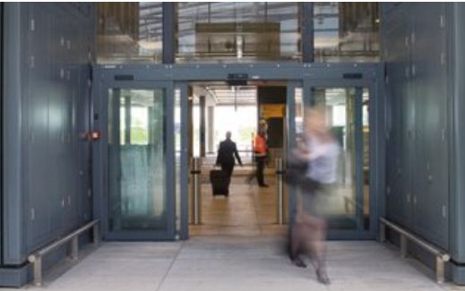 Passenger walking through sliding door entrance at Heathrow Aiport