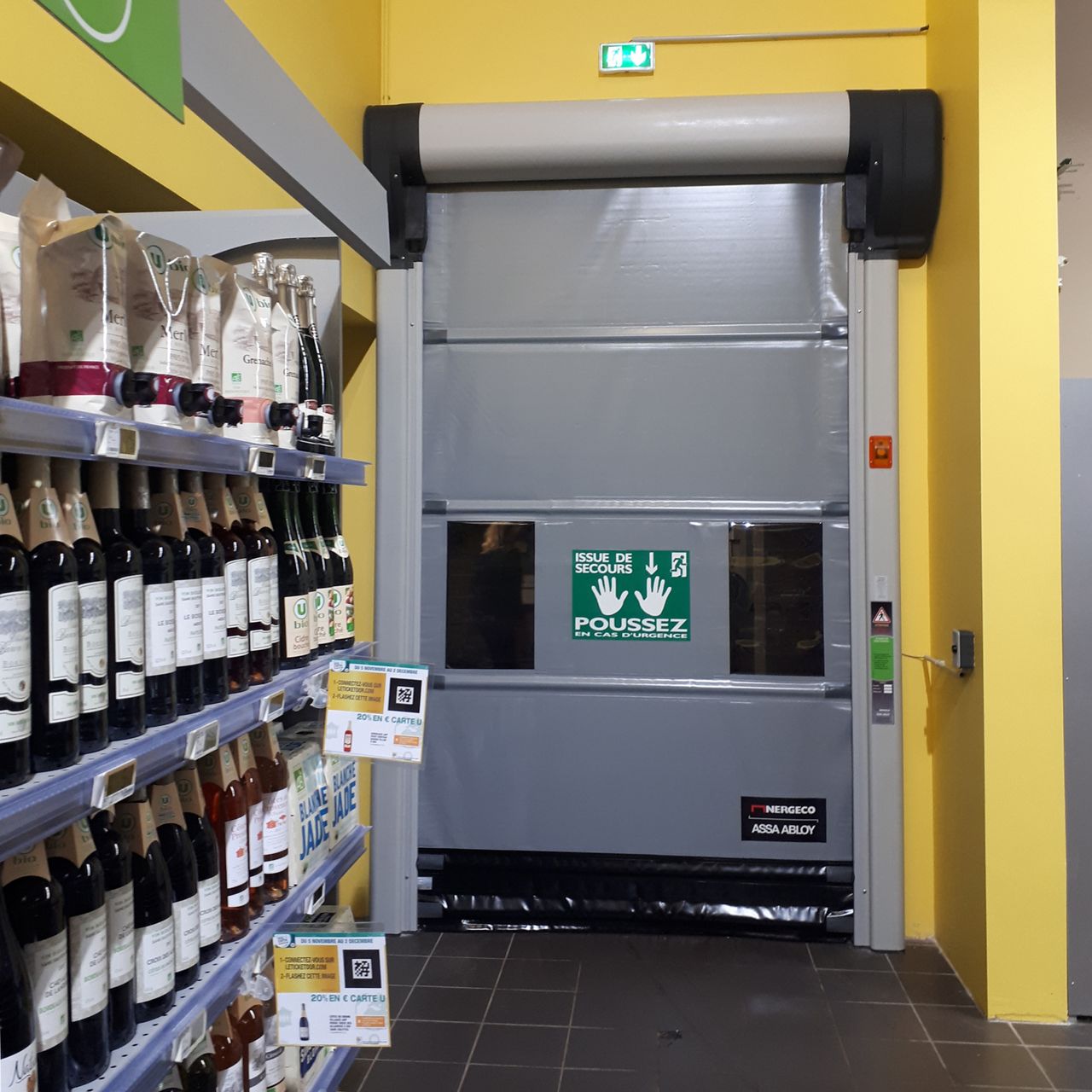 Porte rapide issue de secours en grande distribution entre surface de vente et réserves