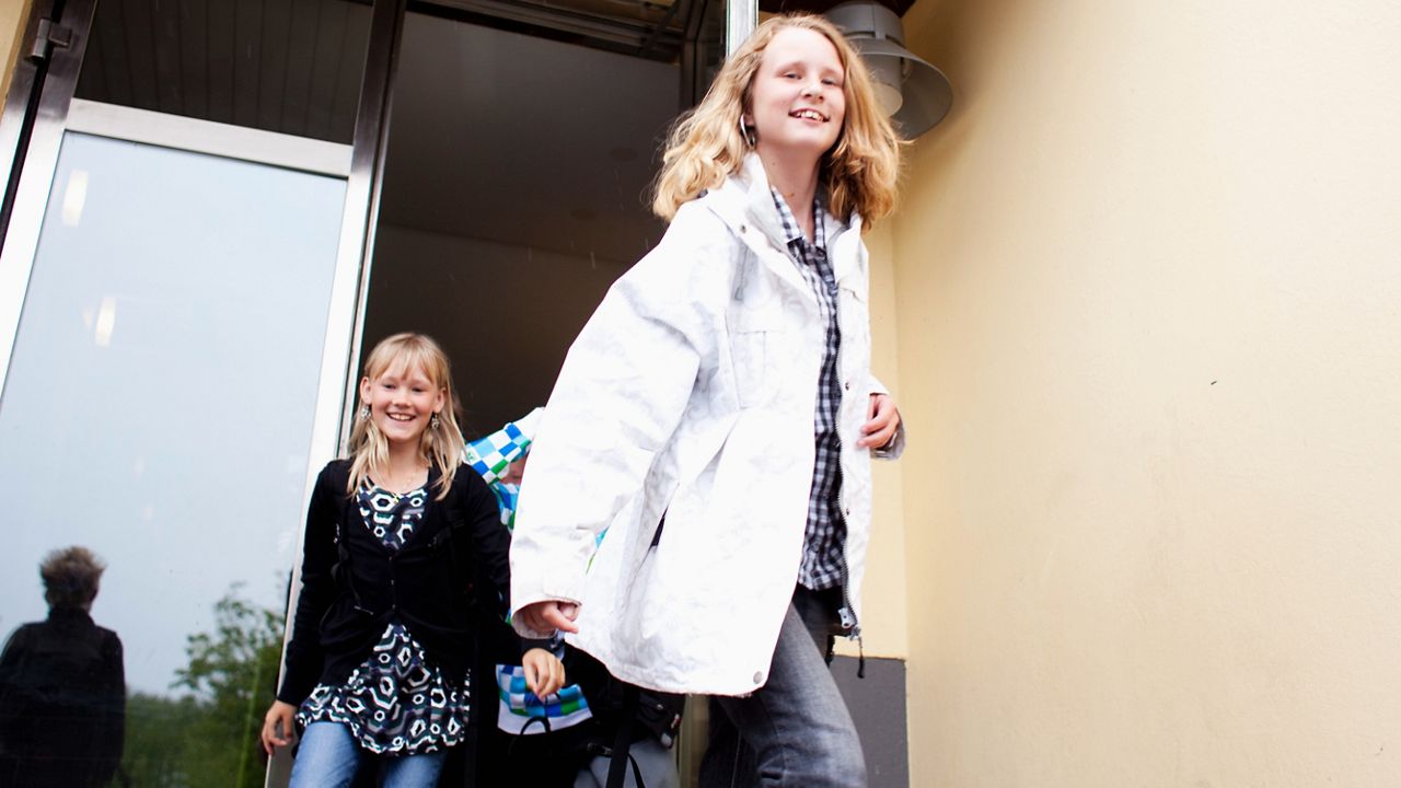 Stundenter på grundskola går ut genom dörren ut på skolgården.