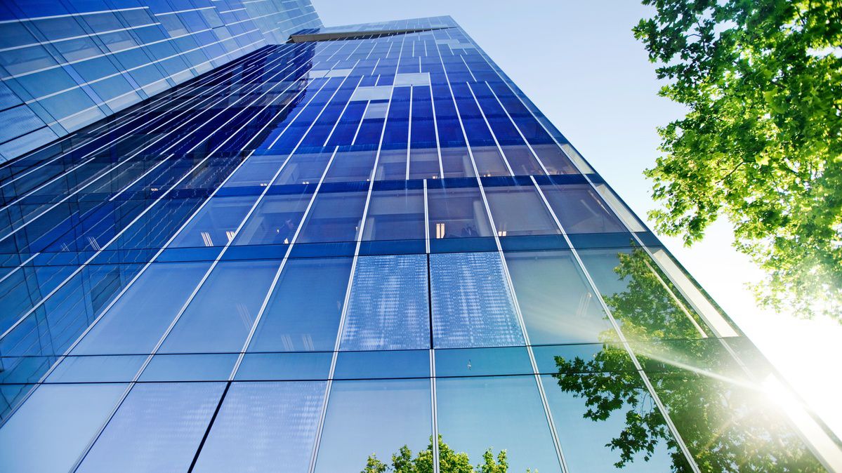 Solen lyser på en byggnad där fasaden är av glas.