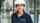 A smiling woman with an ASSA ABLOY branded sweater and a white safety helmet.