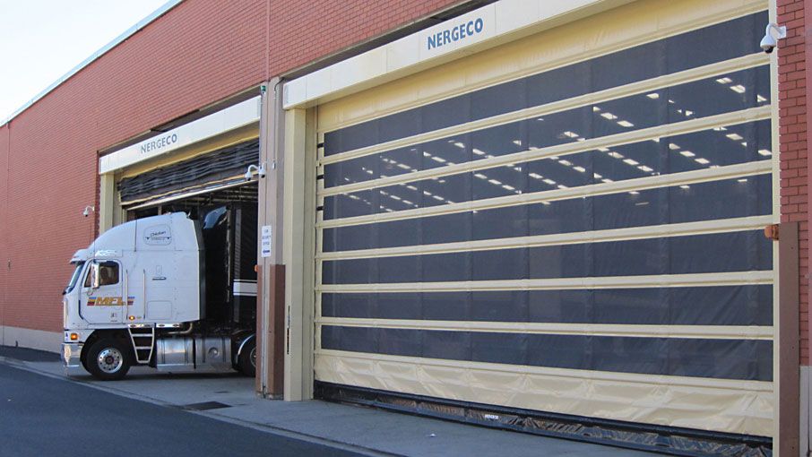 Un camión que sale por una amplia puerta enrollable Nergeco.