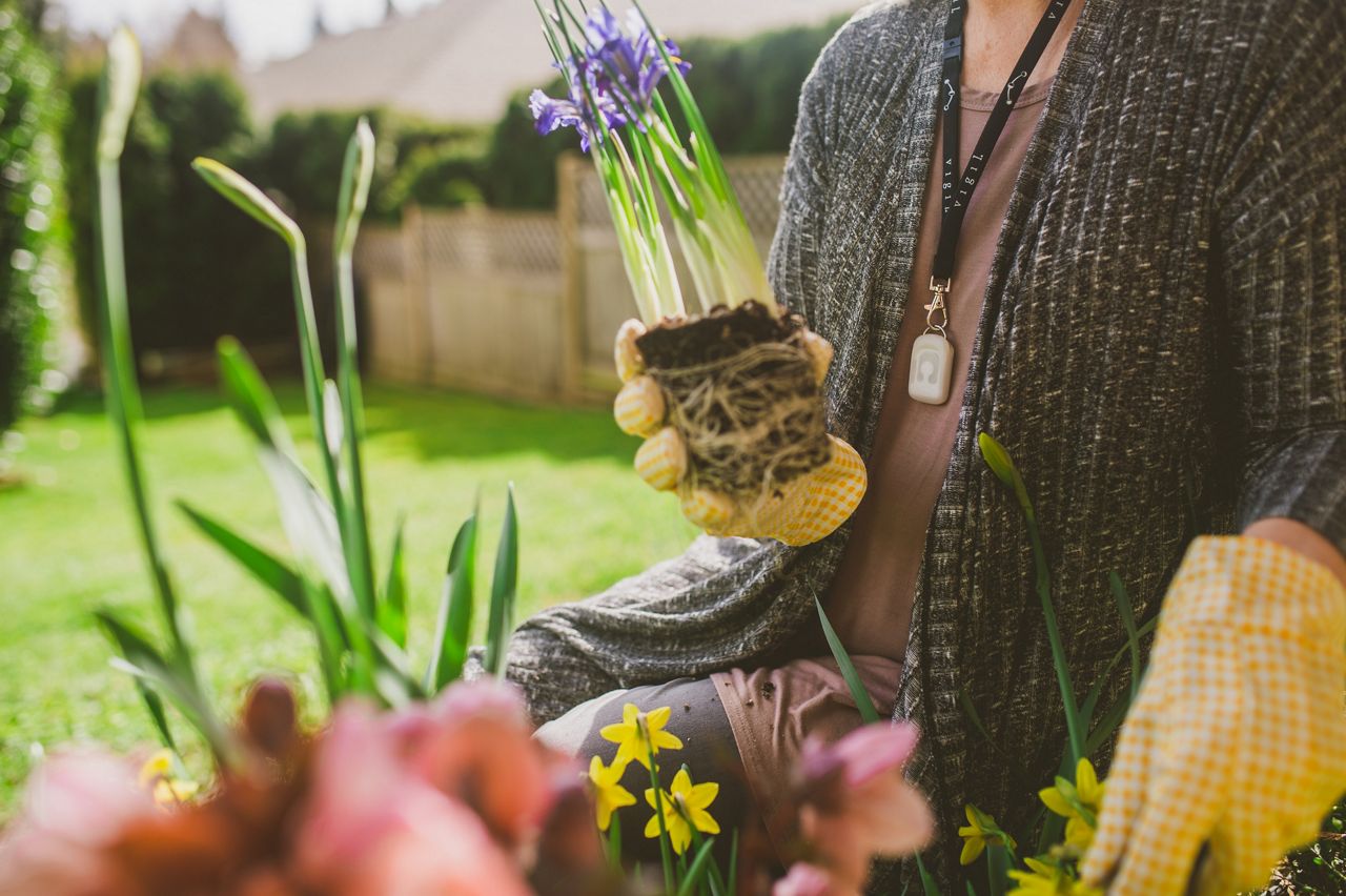 senior woman gardening with vigil pendant on