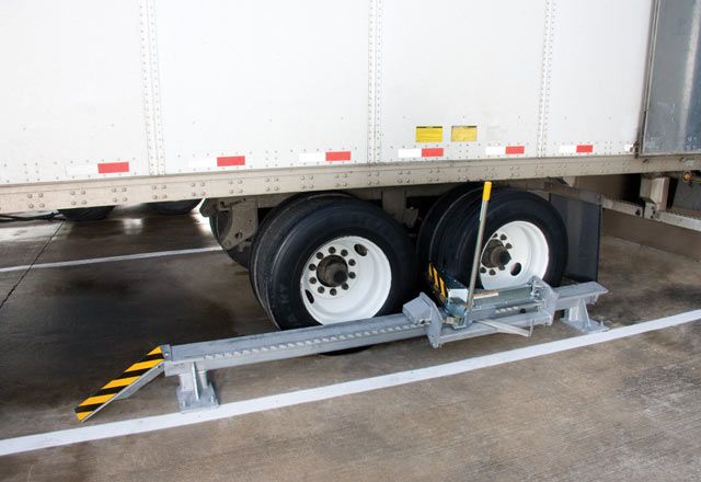 A semi truck being held in place by the Vershachock wheel chocking system