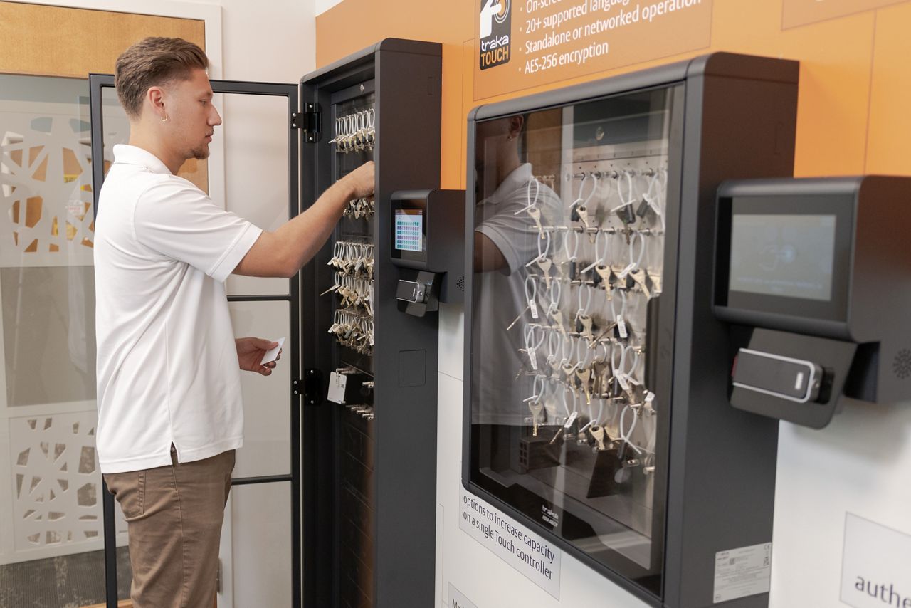 Man pulling keys from a key cabinet system installed in the office