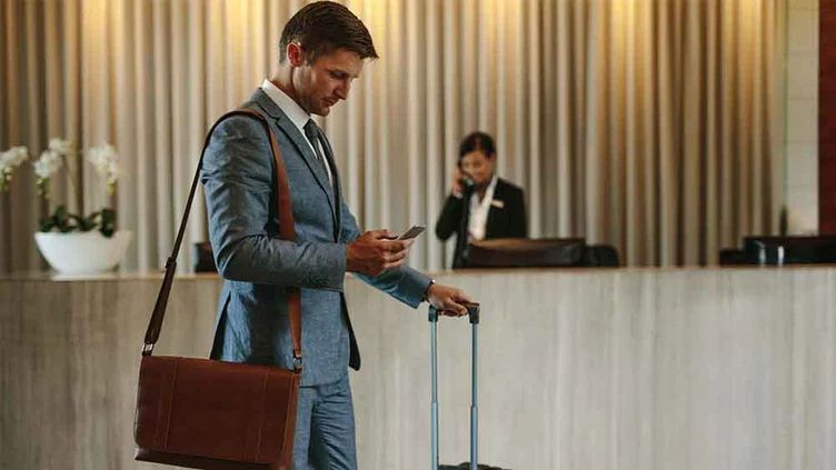 A well-dressed man stands in a hotel lobby, exuding professionalism and elegance.