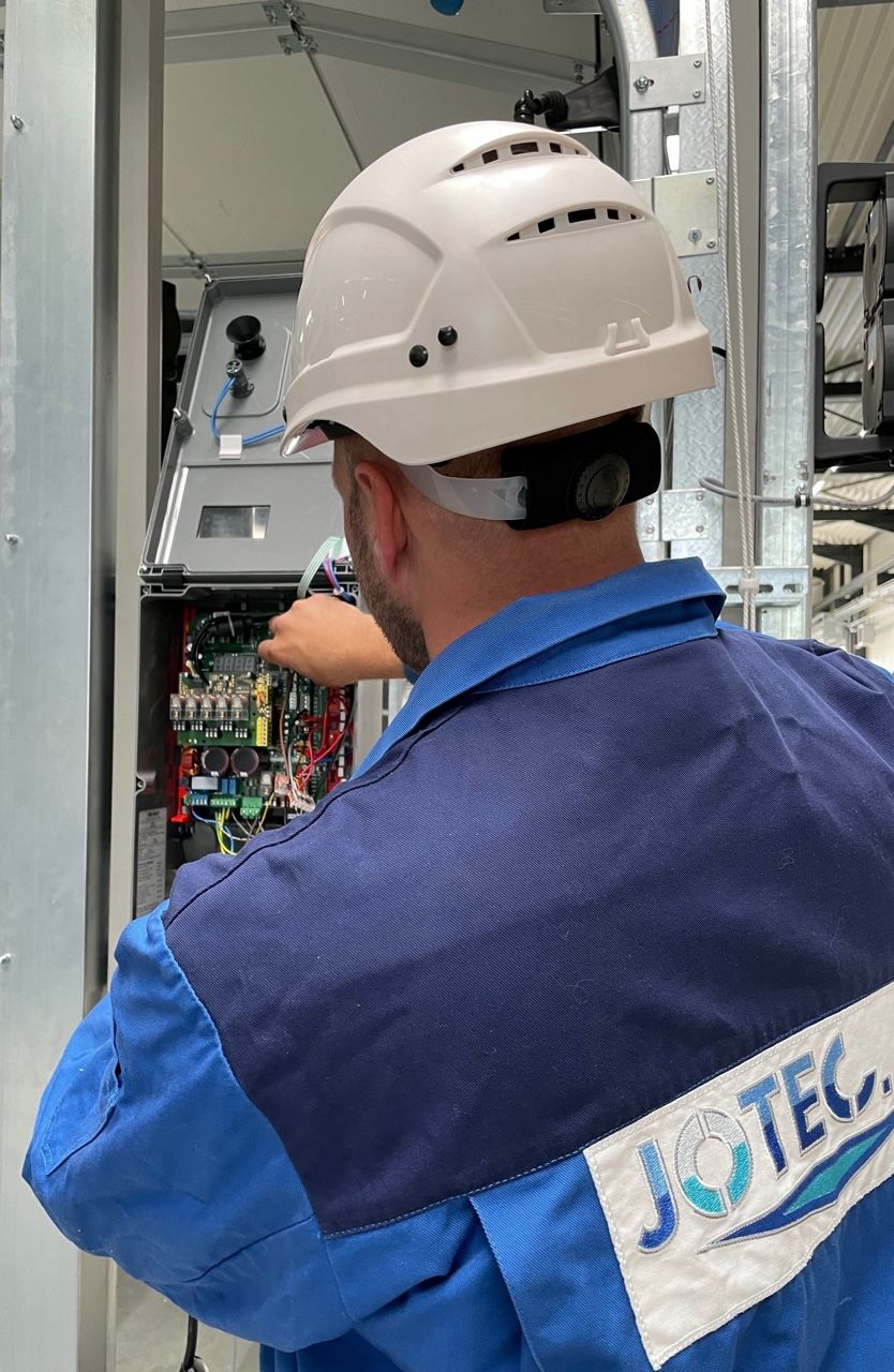 Techniker mit Helm an einer Industrietorsteuerung