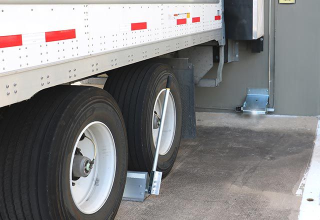 Image: Close up of the Versachock™ Wheel Chock Wireless Restraint in use under a white truck.