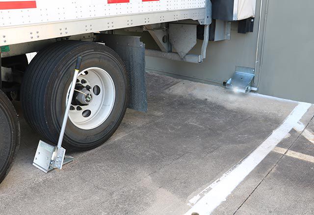 The Versachock™ Wheel Chock Wireless Restraint in use under a white truck.