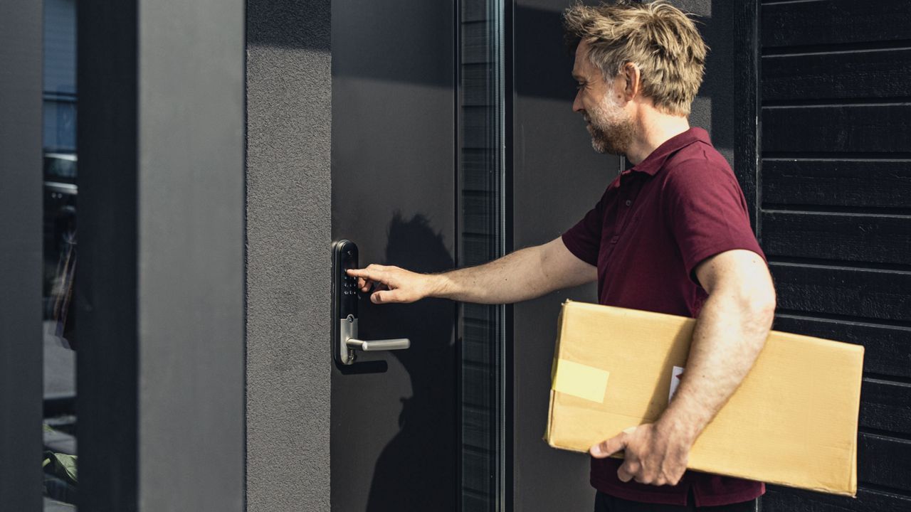 En mand åbner sin hoveddør med at trykke en kode på Yale Doorman smart lås