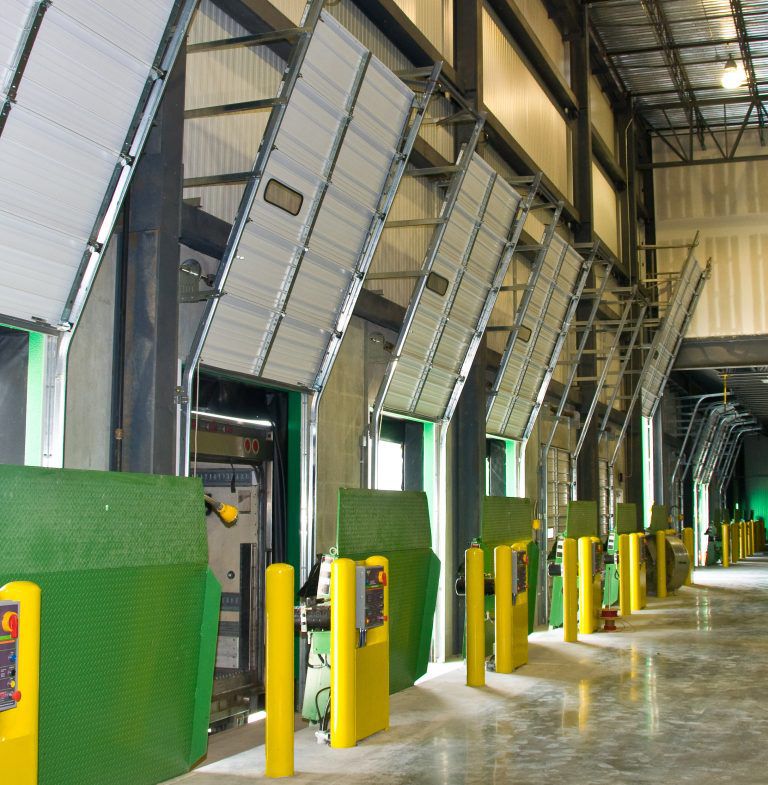 A line of green vertical storing loading docks inside of a warehouse