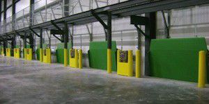 A line of green vertical storing loading docks inside of a warehouse