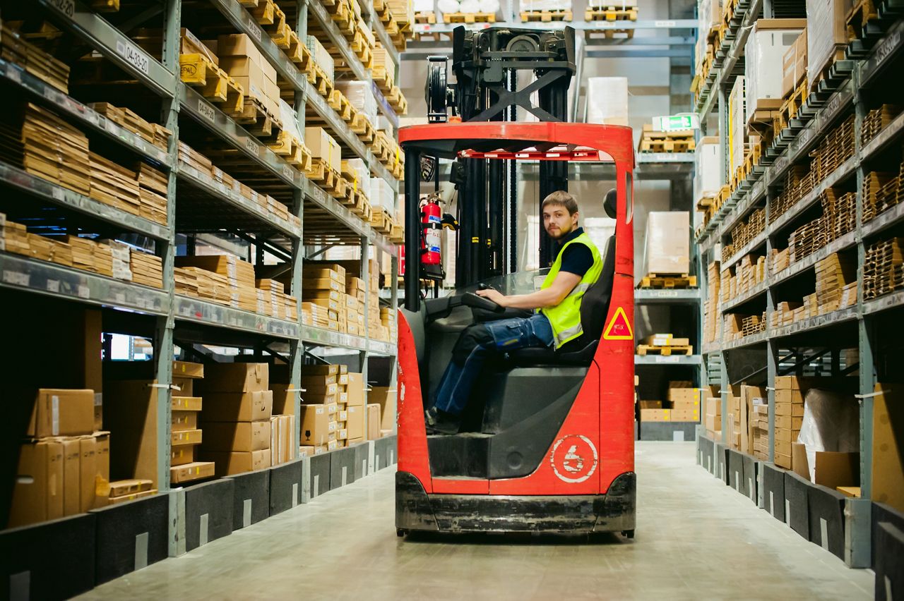 Worker driving a forklift in a distribution warehouse
