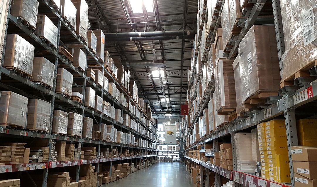 The aisle of a warehouse with tall shelves and a lot of boxes.