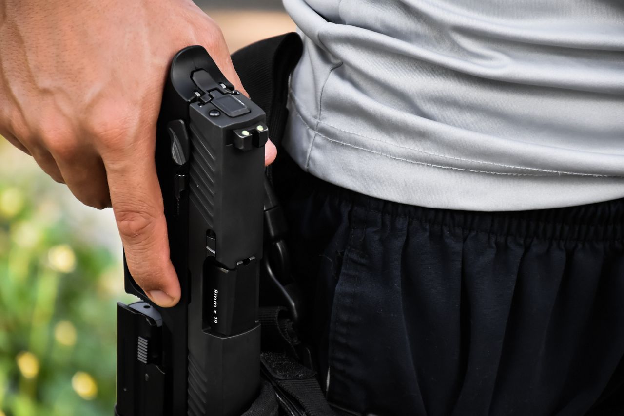Closeup of man holstering a handgun