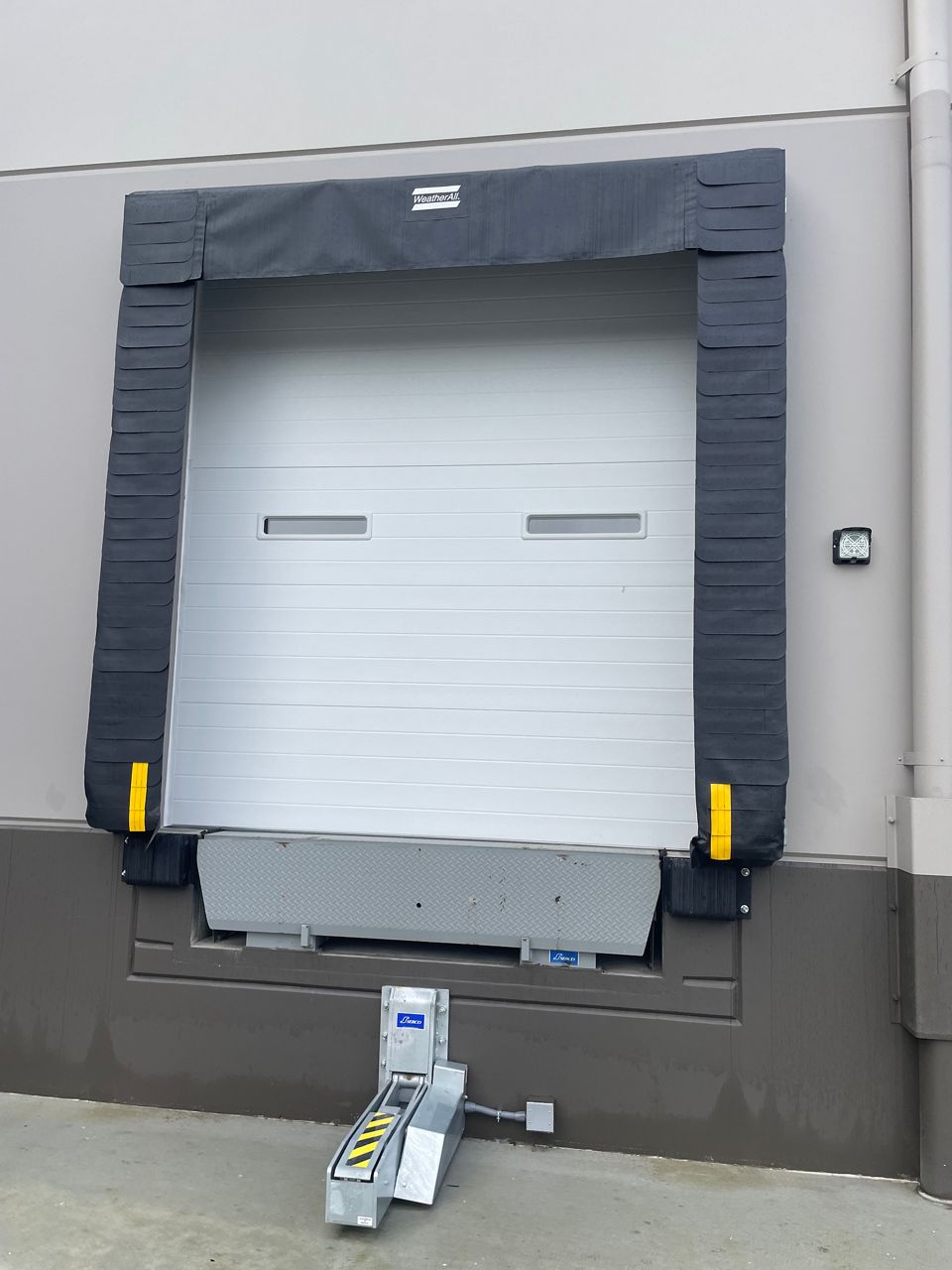 A black WeatherAll Seal on a white door outside of a warehouse