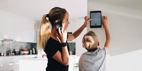 Telefonující žena a chalpec dotýkající se obrazovky domovního systému