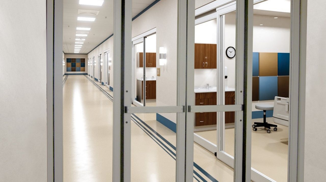 Porte pliante automatique ASSA ABLOY SW200i-Fold dans un couloir d’hôpital.