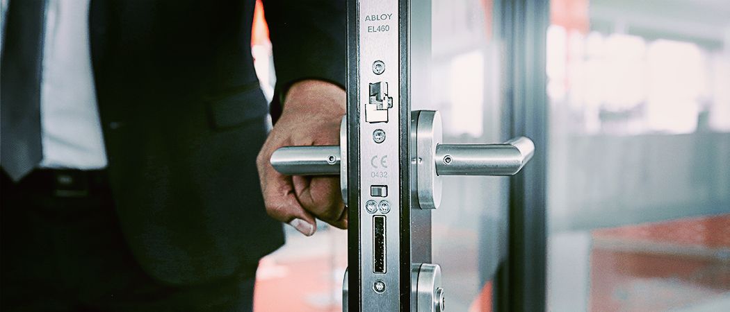 Uomo apre una porta dove è installata una serratura Abloy
