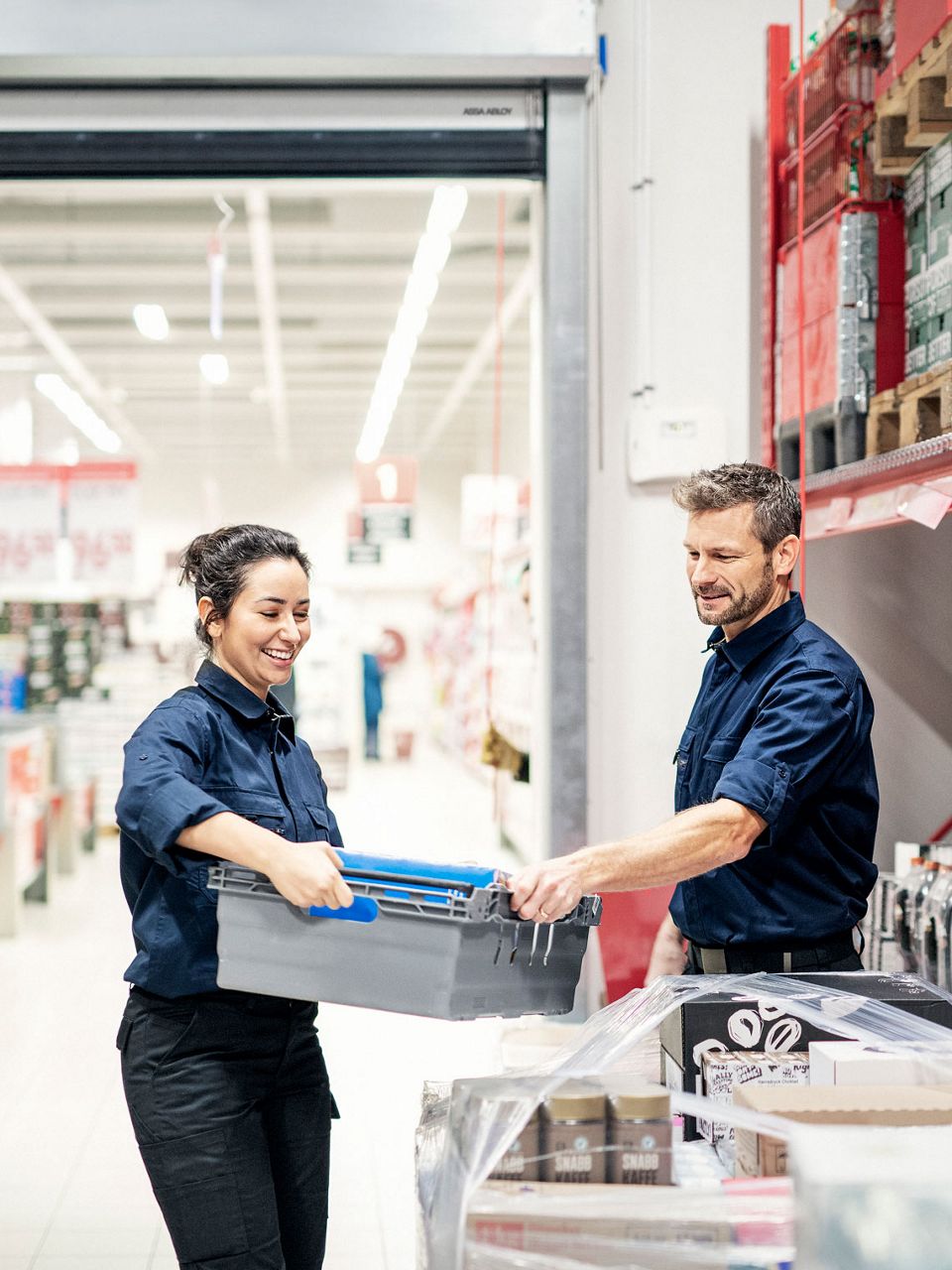 Two coworkers helping out at a grocery store warehouse. 
