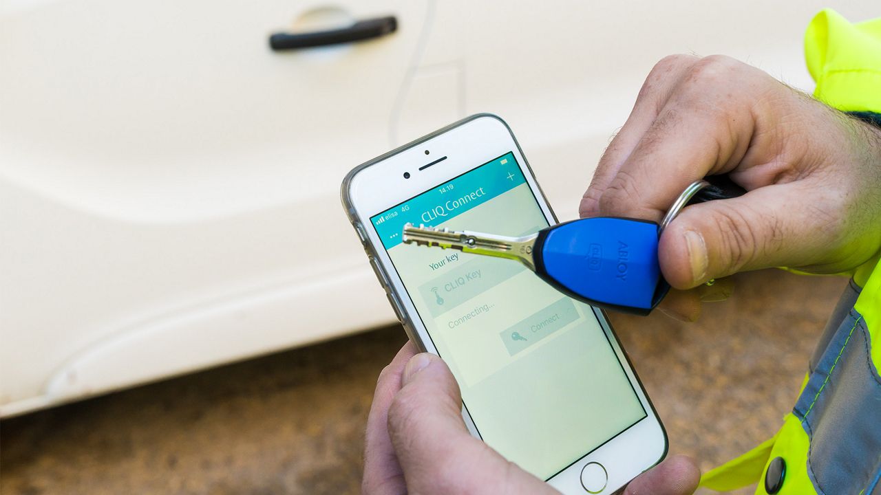 Teléfono inteligente con una aplicación en pantalla y una llave ABLOY.