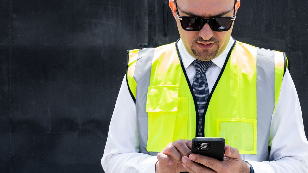 Un homme regarde l’écran d’un téléphone portable.