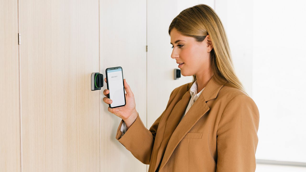 Kobieta otwiera zamek za pomocą aplikacji mobilnej.