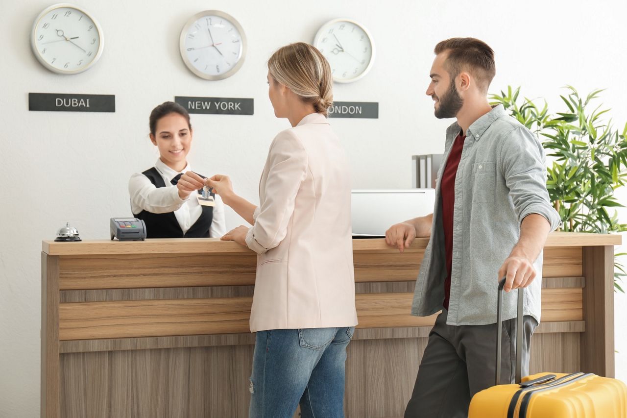 Young couple receiving key from hotel room at reception