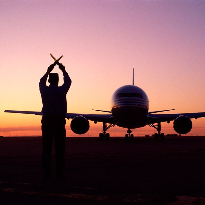Airport straff guiding a plane. 