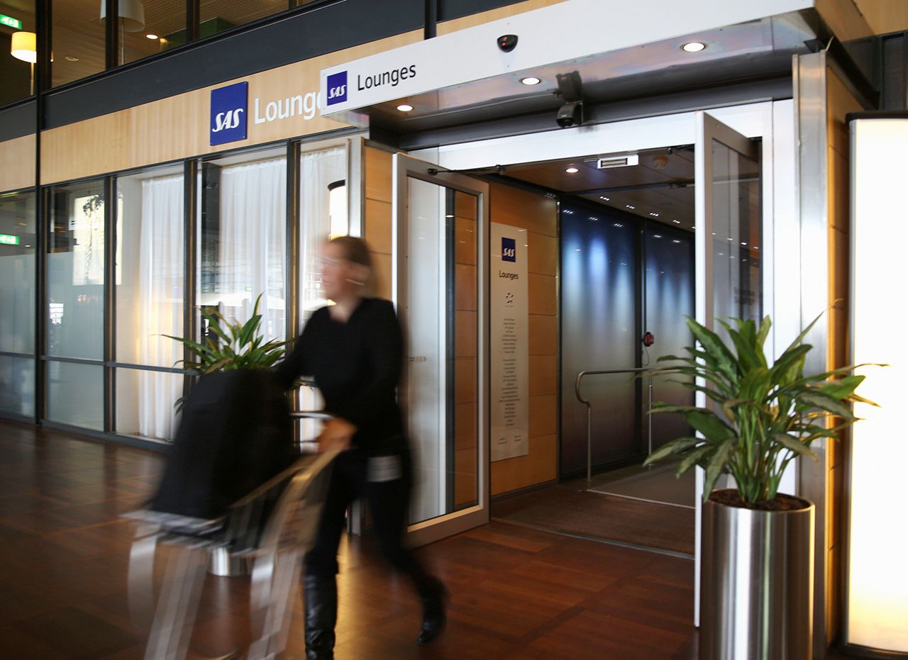 Kvinne på vei ut av SAS-loungen på en skandinavisk flyplass med babage på vogn.