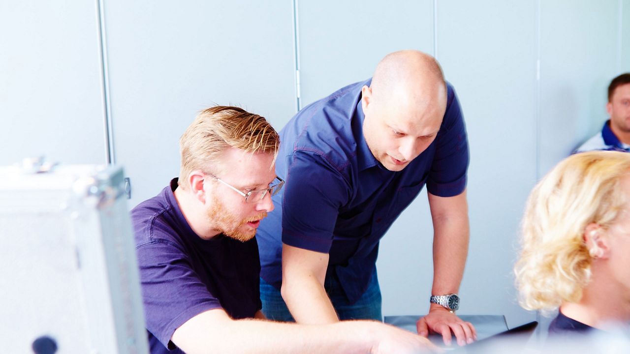 Two men are leaning over something in a conference room.