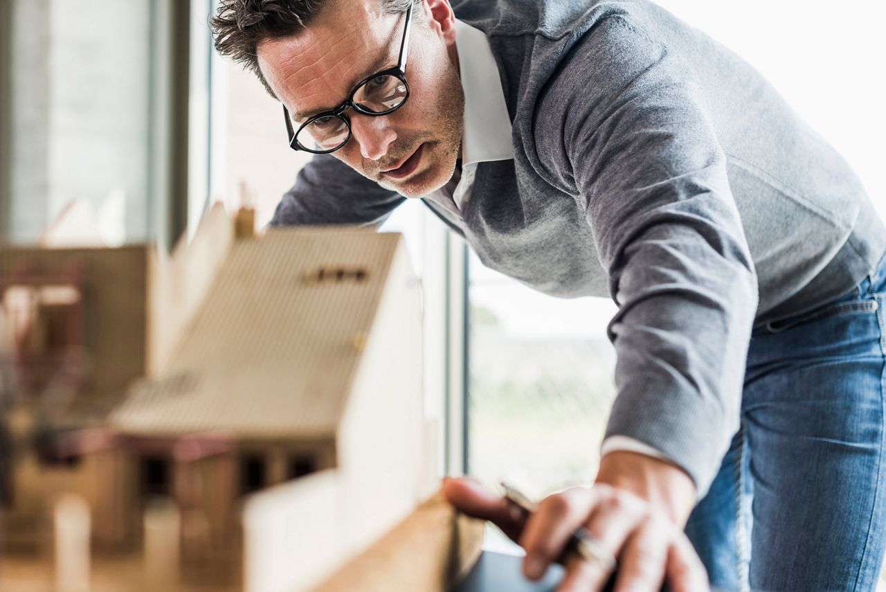 Homme qui dessine des plans sur une table d'architecte grâce aux conseils et tutos de Vachette / ASSA ABLOY