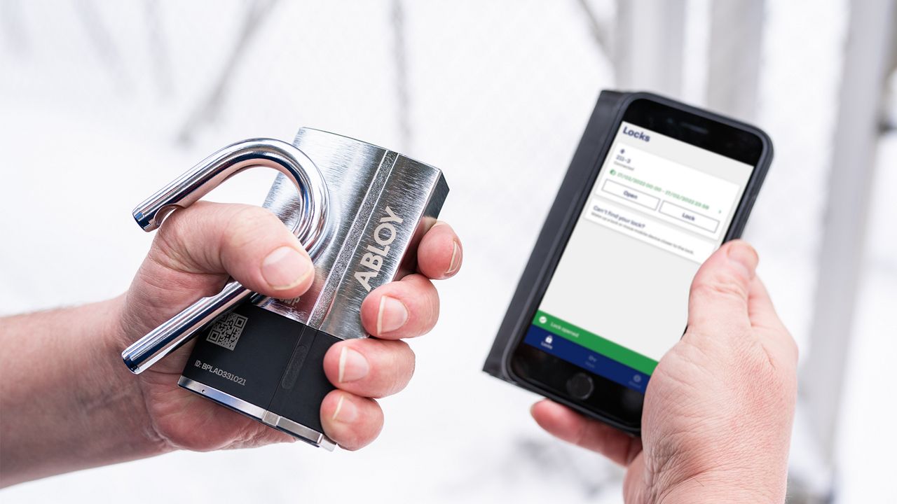 Padlock and mobile screen held by a person.