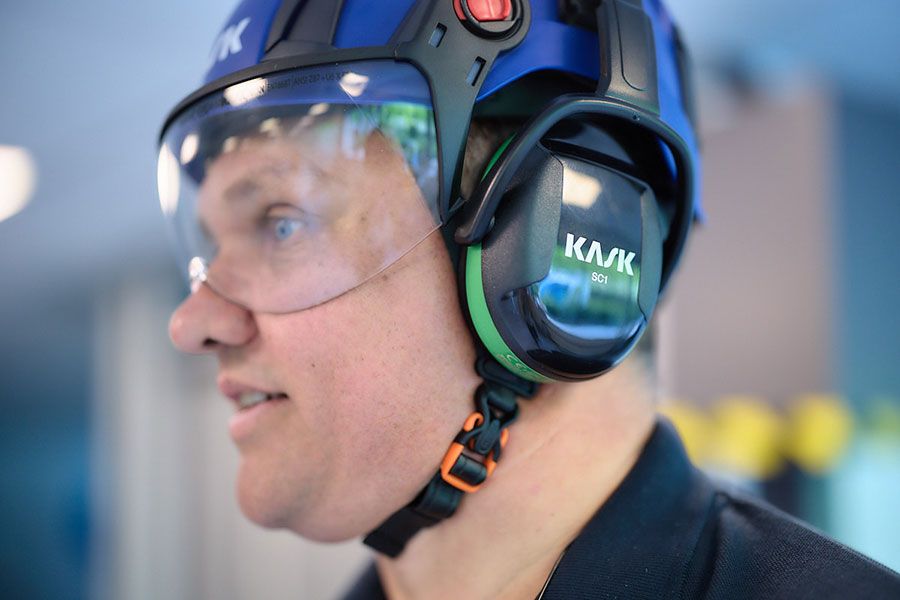 Employé d'ASSA ABLOY portant un casque de sécurité, une protection auditive et des lunettes de protection.