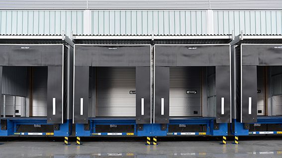Een rij laadkades uitgerust met ASSA ABLOY systemen, waaronder een dock shelter met flappen voor bescherming tijdens het laden en lossen.