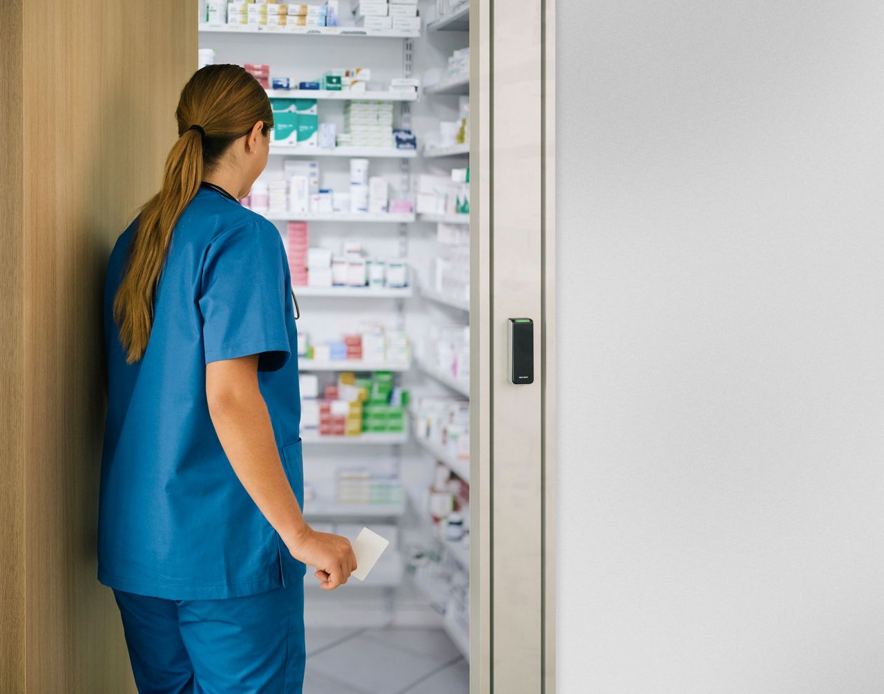 Verpleegkundige kijkt door medicijnkast.