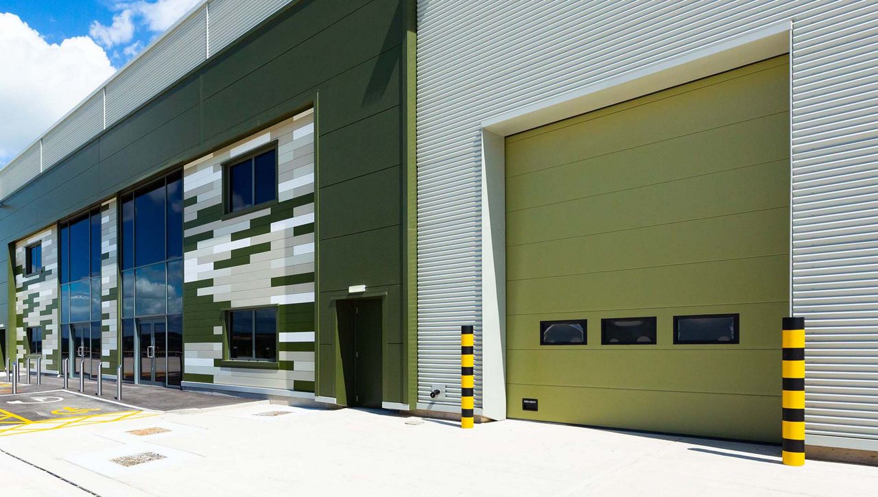 A Crawford OH1042P level access sectional door, specially supplied in a non-standard Khaki Green to harmonise with the building's cladding.