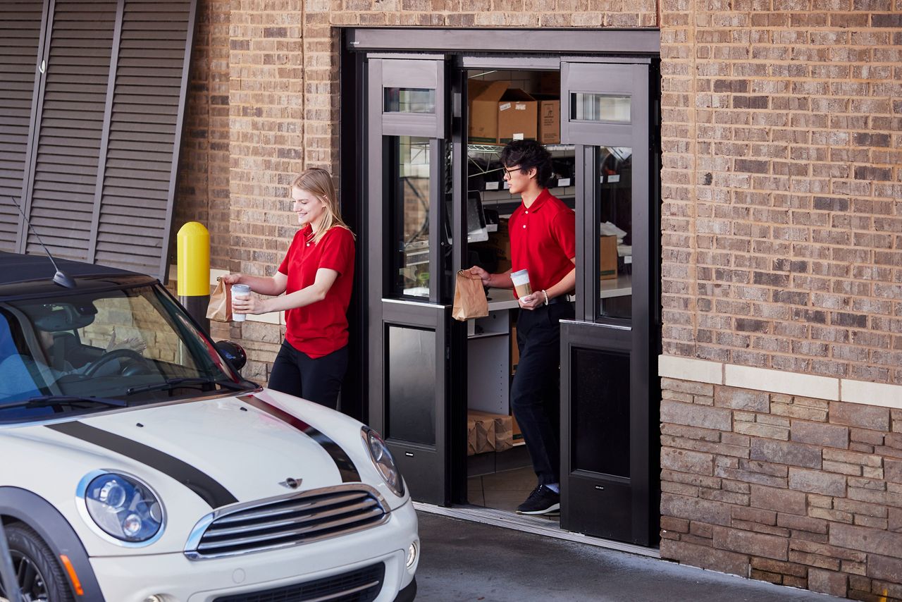 A QSR employee serves customers conveniently with the help of an ASSA ABLOY automatic door