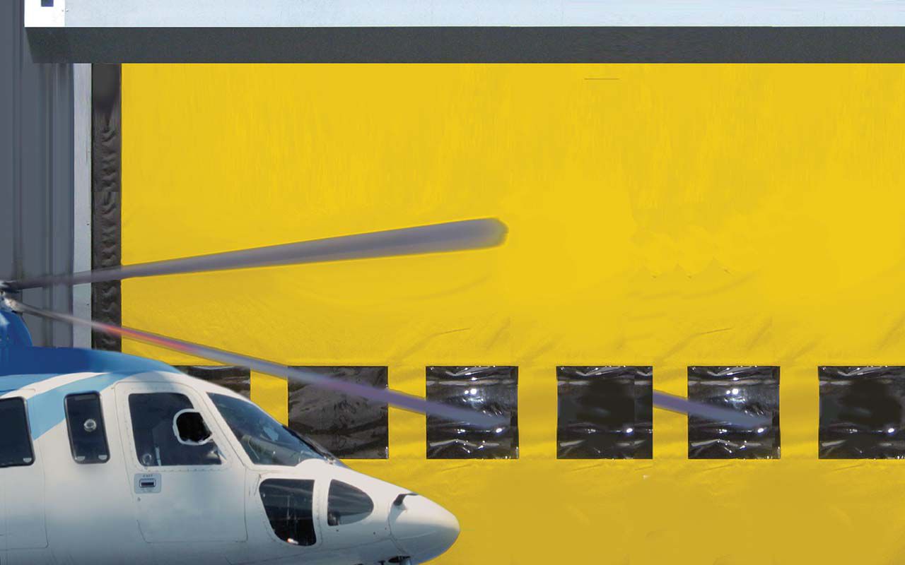 Ein großes gelbes Tor mit Fenstern und einem Hubschrauber davor. 