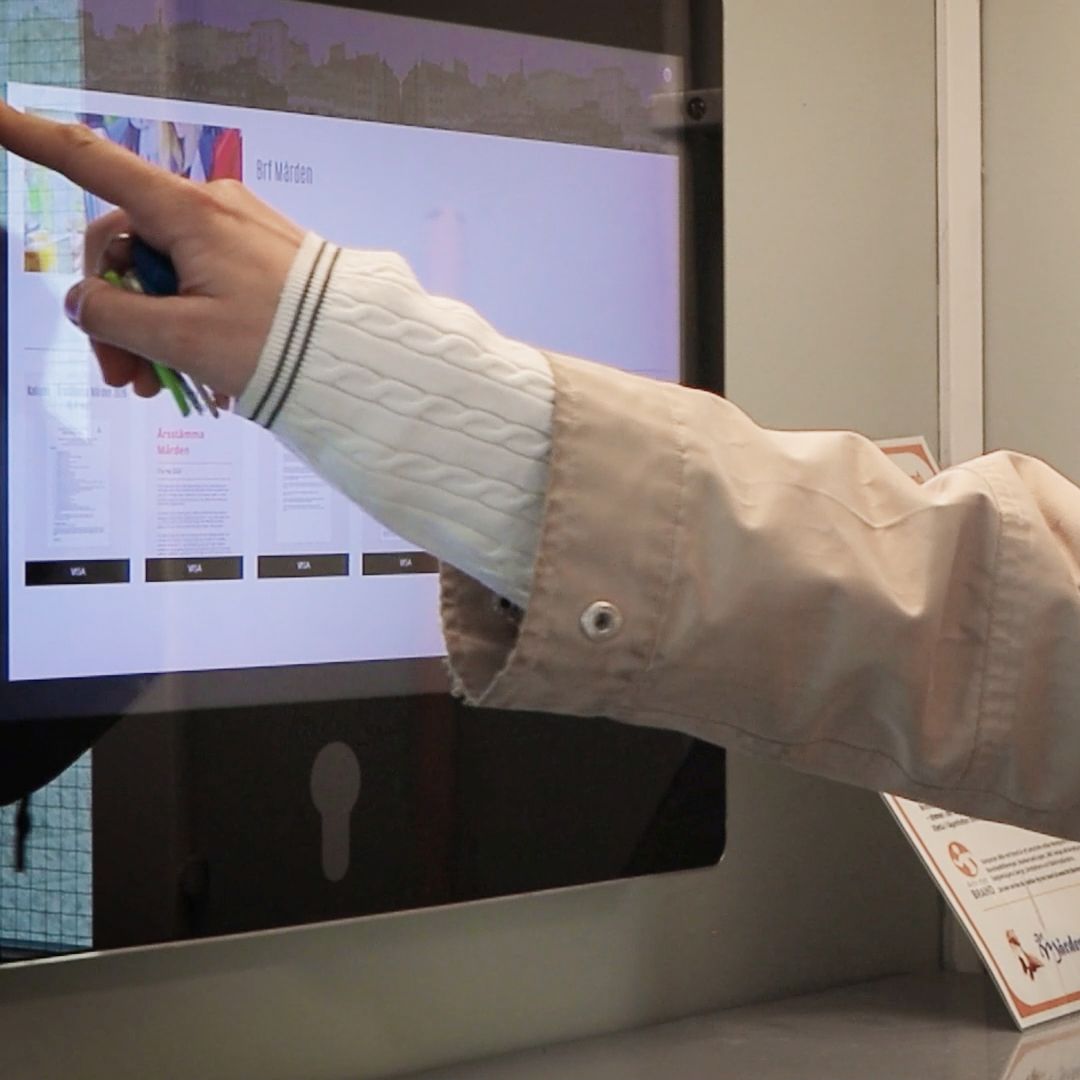 En hand och en arm framför en digital informationstavla.