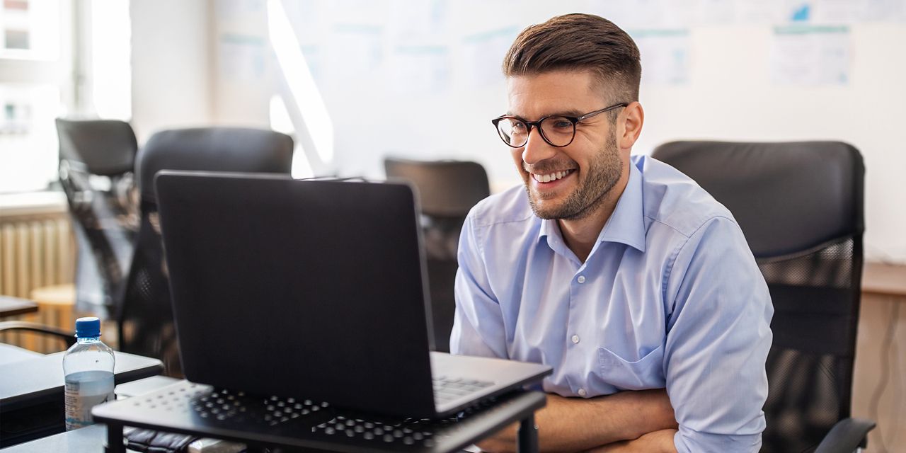 Businessman smiling in front of laptop in office