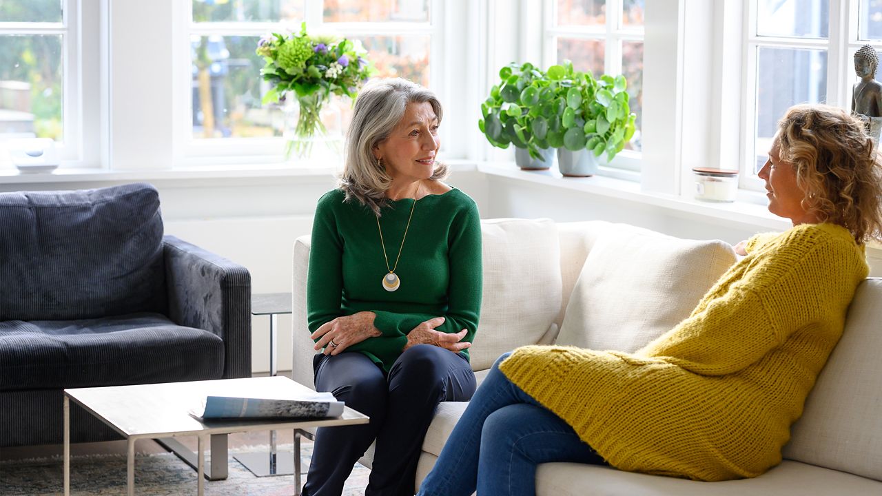 Senior woman with alarm pendant sitting at home talking to a relative.