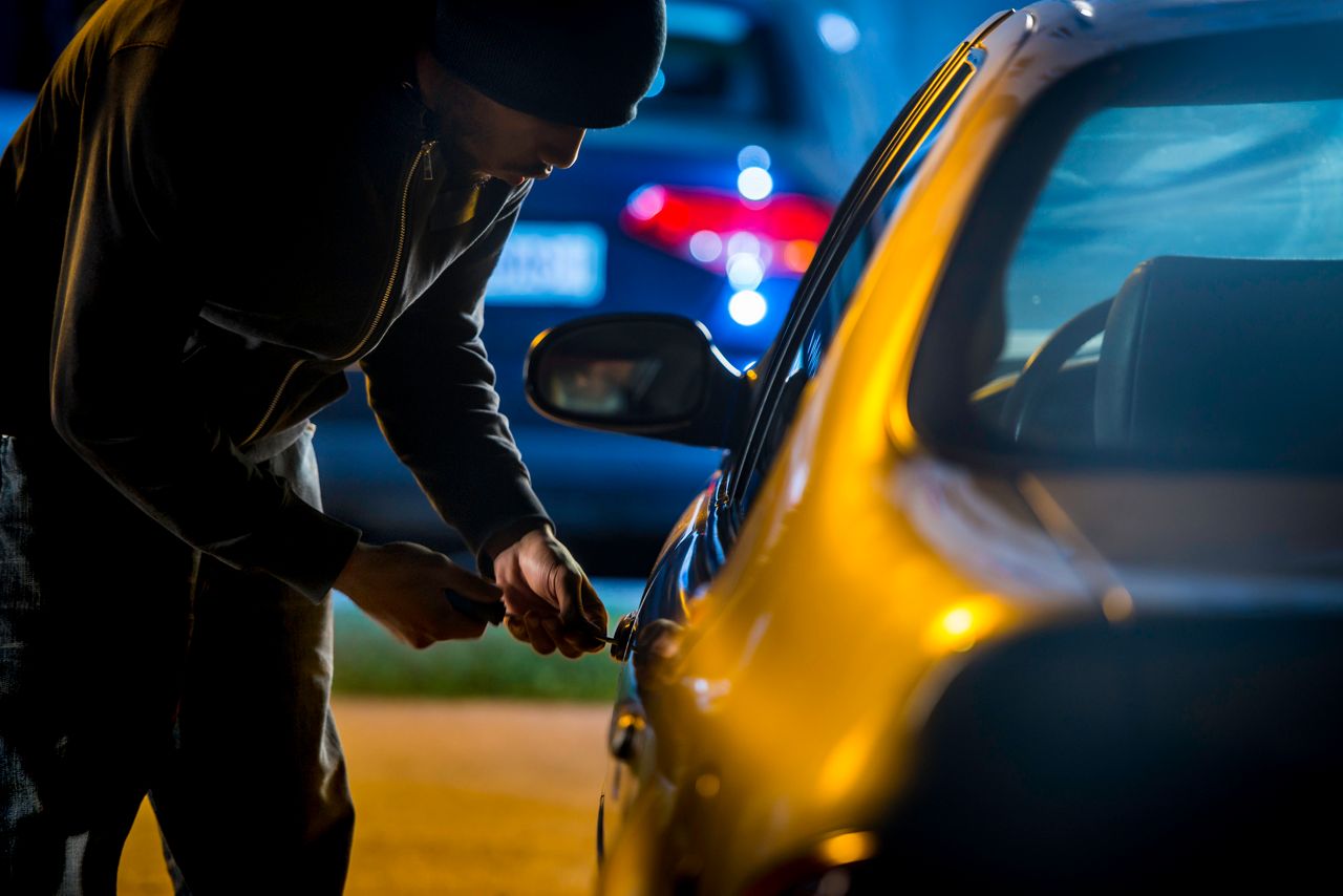 Car thief breaking into vehicle
