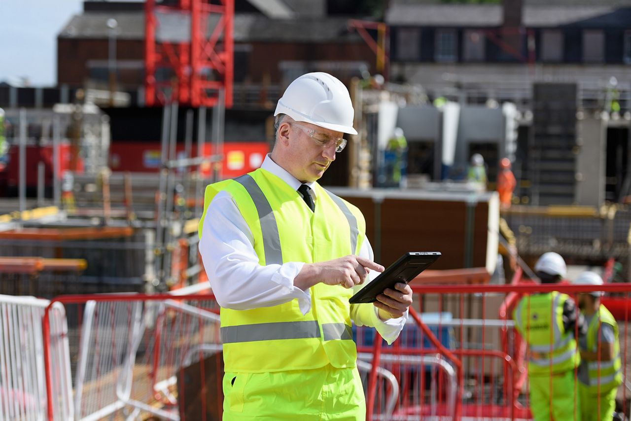 A construction worker holds a tablet device