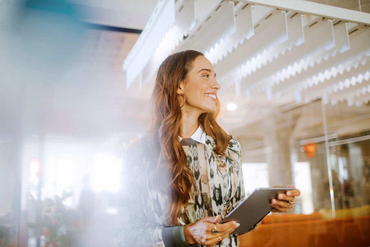 A woman with a tablet smiling in an office
