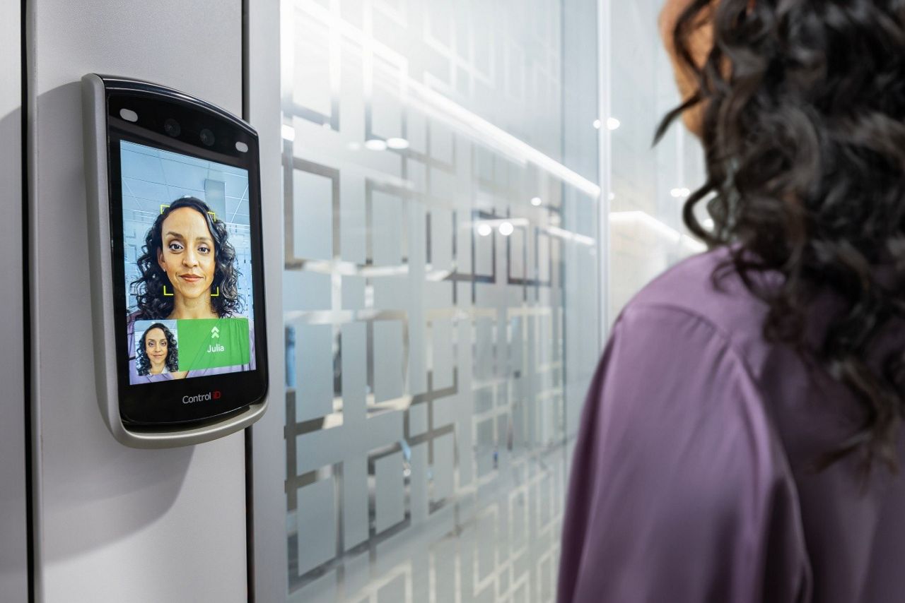 Woman using a Control iD biometric face reader to unlock a glass door