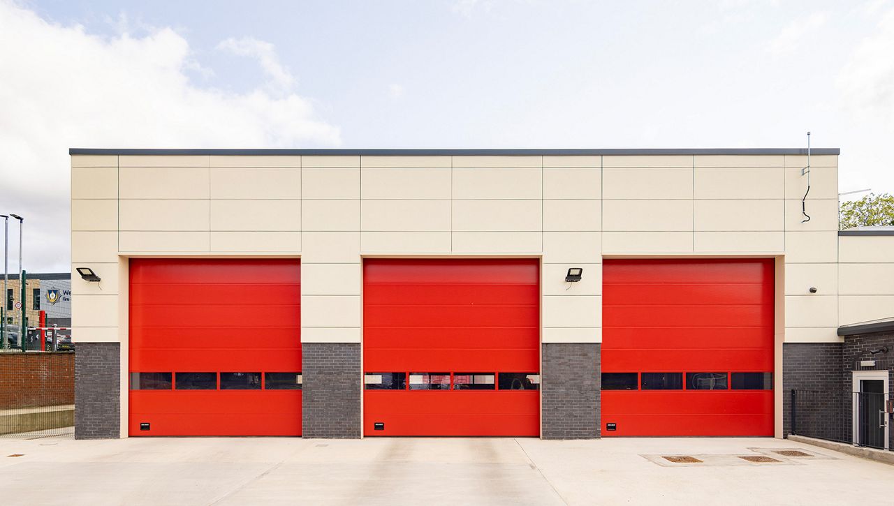 An external image of a three Crawford OH1042S overhead sectional doors in row at a UK fire station