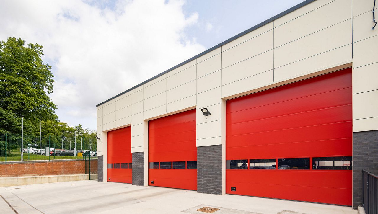 Image: A row of Crawford OH1042S fast opening overhead sectional doors at a fire station