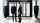 Two people in black clothes standing infront of a glass sliding door.